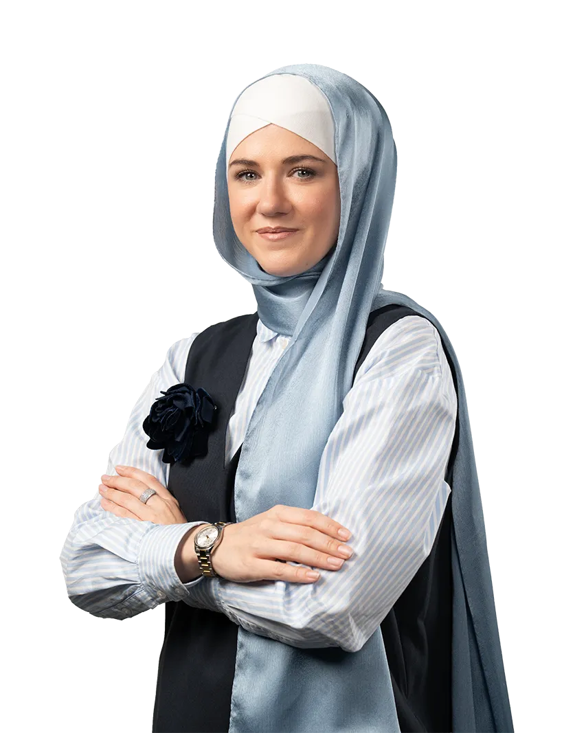 Confident woman wearing a light blue hijab, striped shirt, and dark vest with arms crossed.