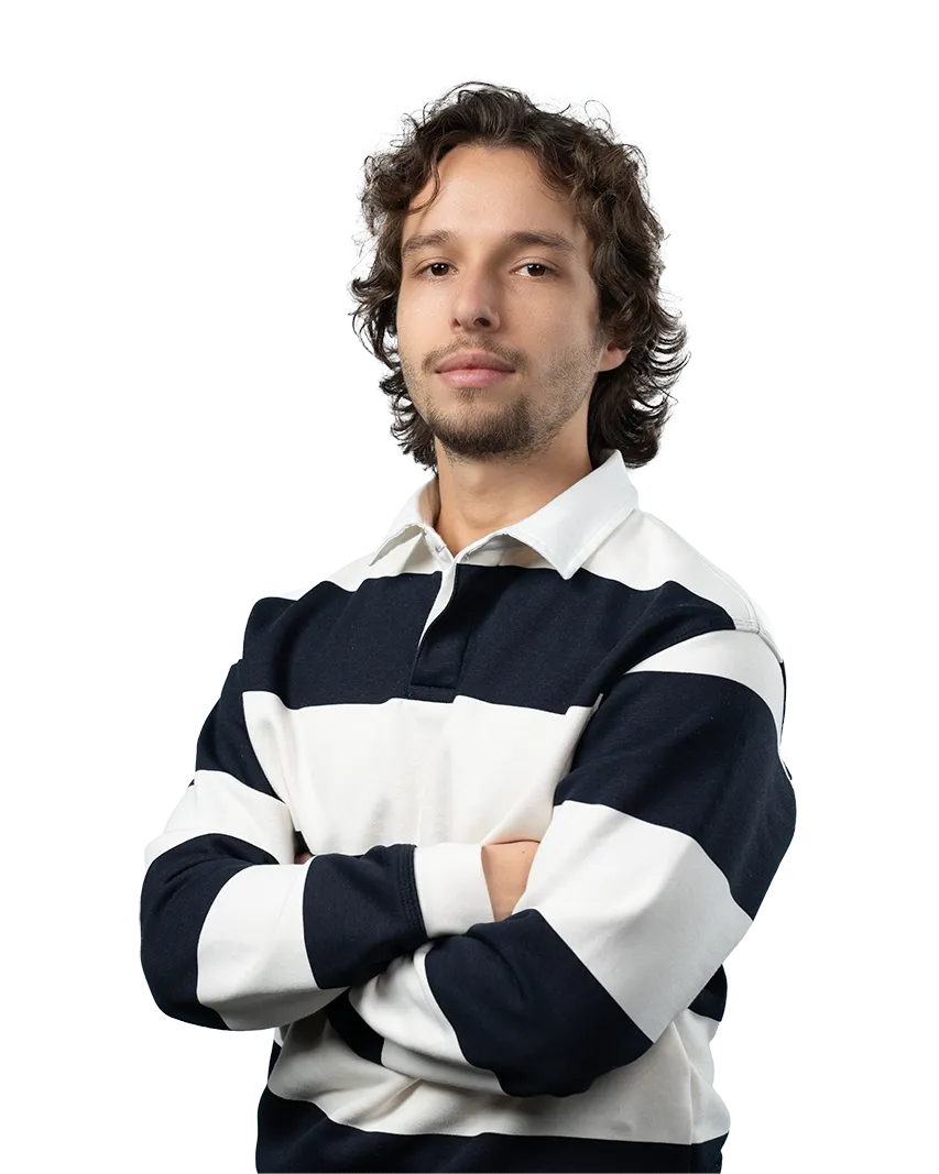 Young man with curly hair and light facial hair wearing a black and white striped rugby shirt with arms crossed.